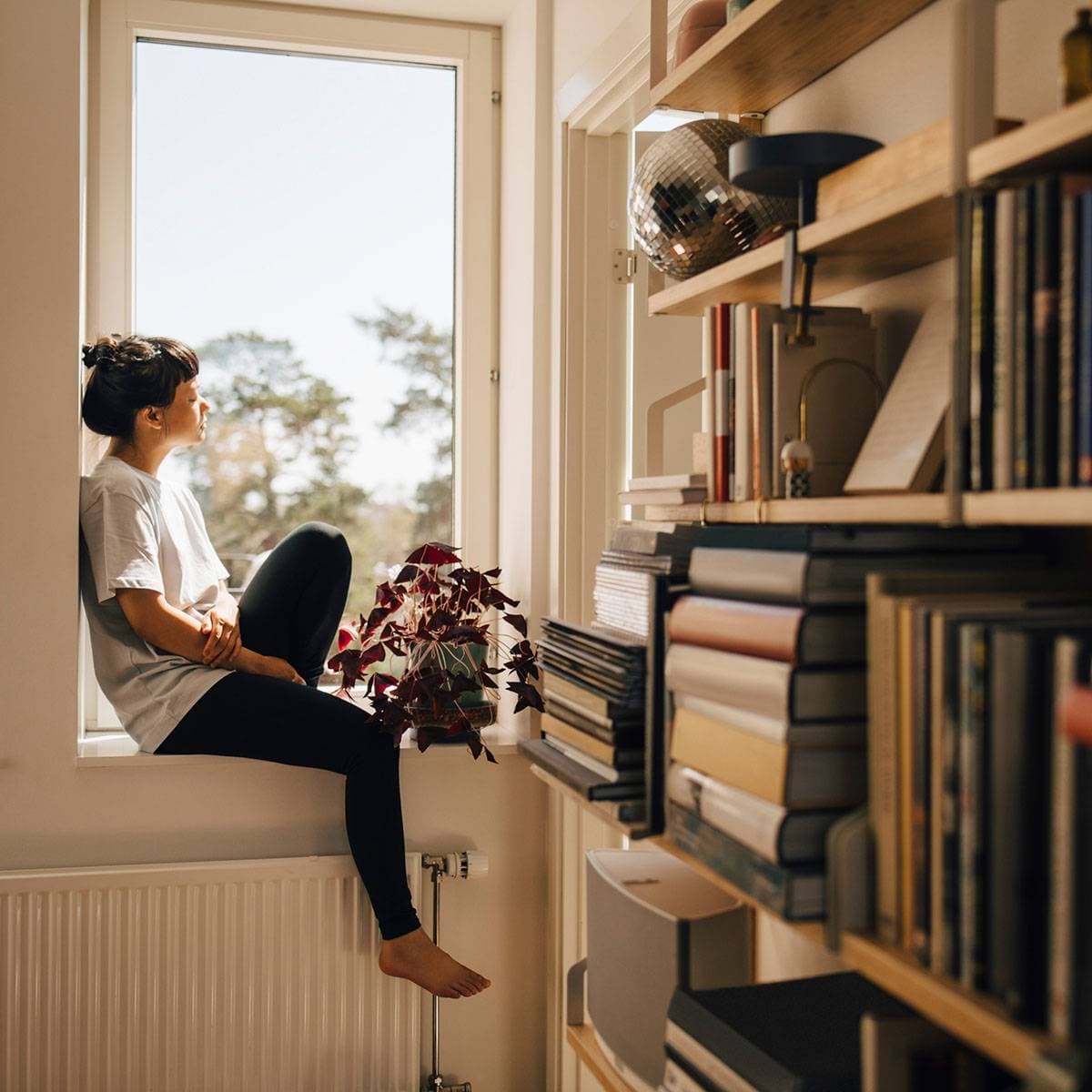 Kvinna sitter vid ett fönster i en lägenhet.