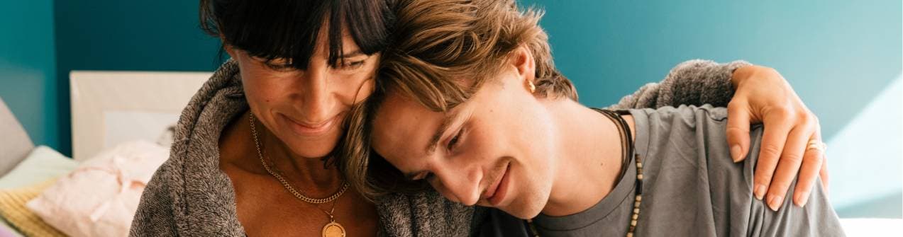 son som lutar huvudet mot sin mamma